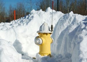 Yellow hydrant with spring flag in a shoveled-out snowbank