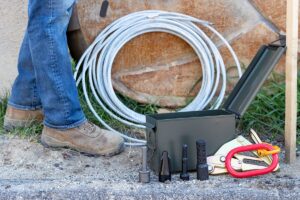 NCT's service line puller kit components and coiled puller cable shown at a worker's feet