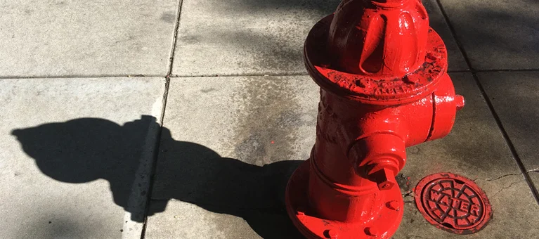 Red fire hydrant casting shadow on sidewalk