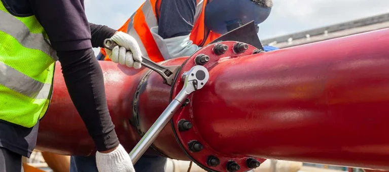 Workers in safety vests using gate valve wrenches in the field